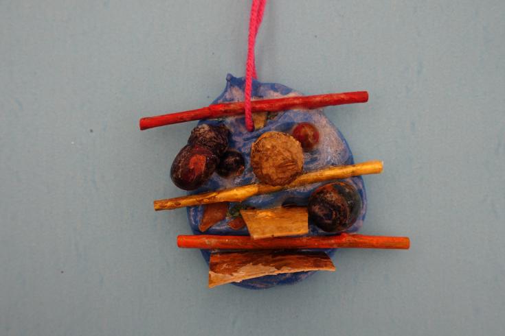 Clay mobile with painted acorns and sticks.