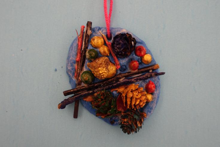 Clay mobile with painted pinecones and sticks.