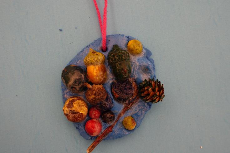 Clay mobile with painted pinecones and holly.