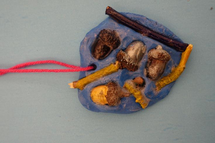 Clay mobile with painted acorns and sticks.