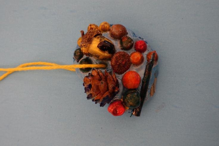 Clay mobile with painted pinecones and acorns.