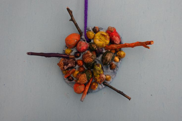 Clay mobile with painted sticks and acorns.