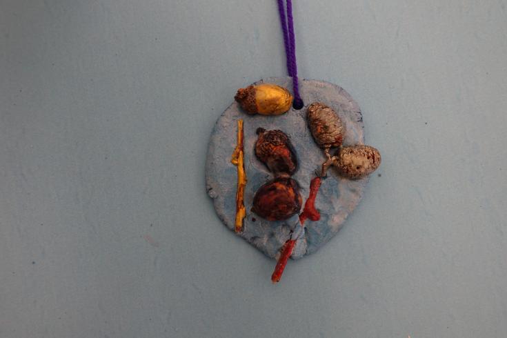 Clay mobile with painted acorns and sticks.