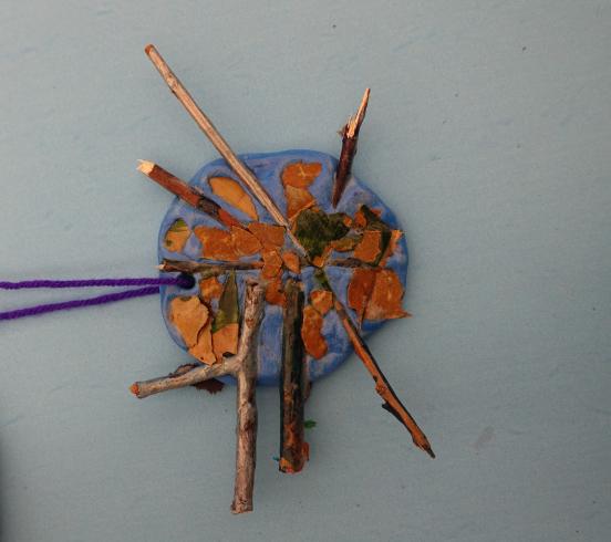 Clay mobile with painted sticks and leaves.