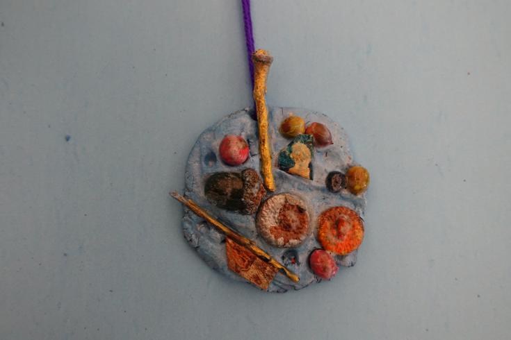 Clay mobile with painted acorns and sticks.