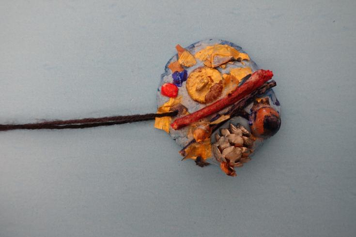 Clay mobile with painted pinecones and sticks.