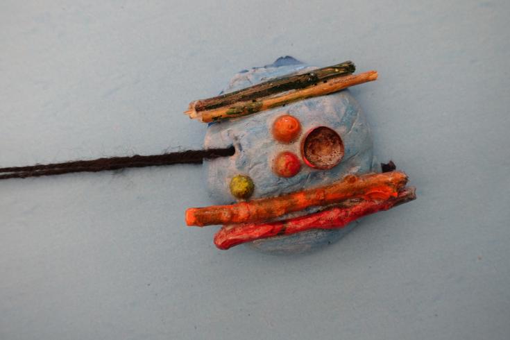 Clay mobile with painted sticks.