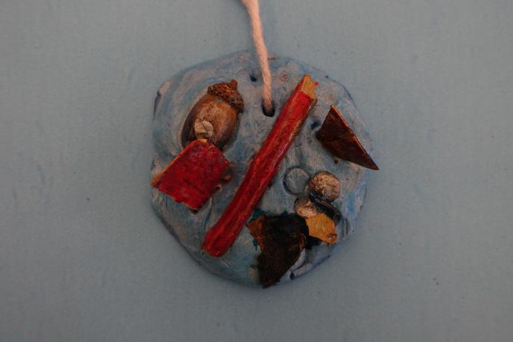 Clay mobile with painted acorns, sticks, and wood chips.