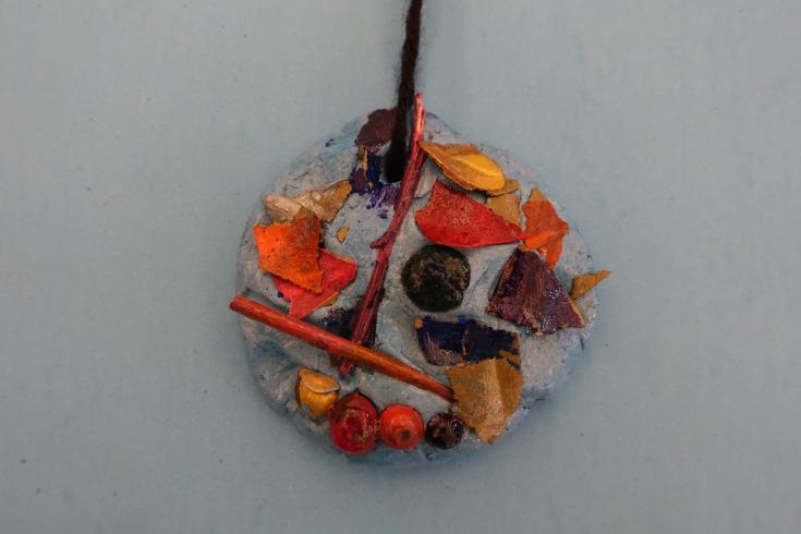 Clay mobile with painted wood chips, acorns, and sticks.