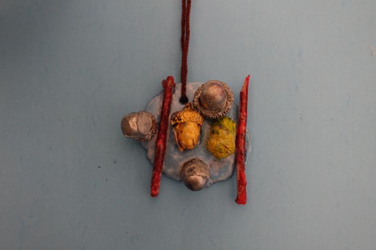 Clay mobile with two painted sticks and acorns.