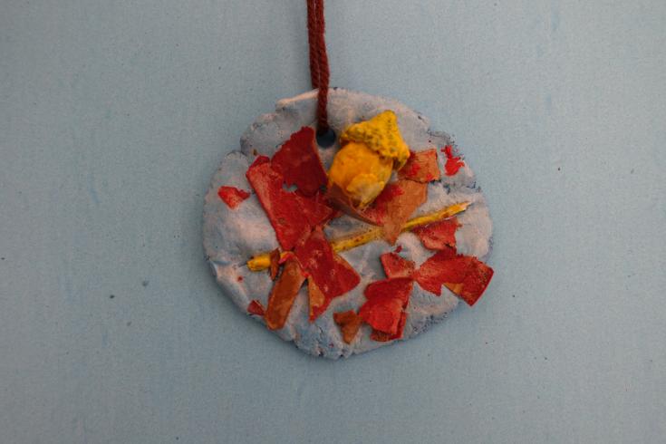 Clay mobile with painted leaves and an acorn.