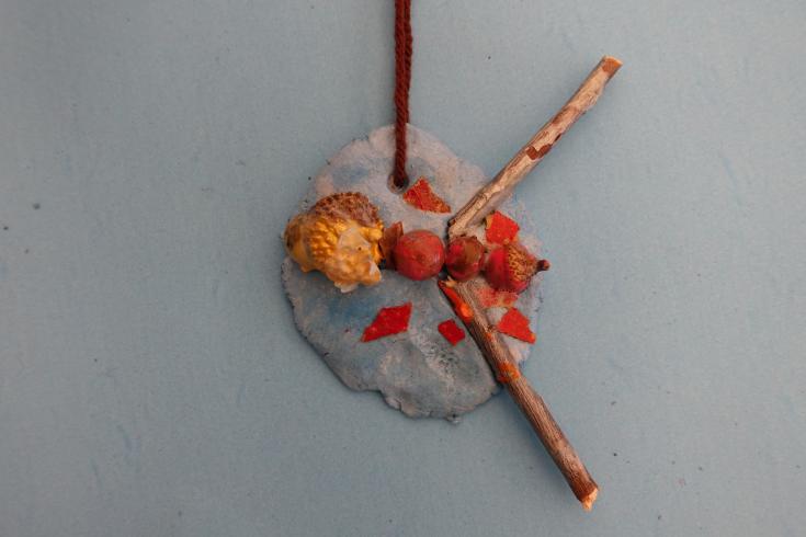 Clay mobile with sticks and painted acorns.