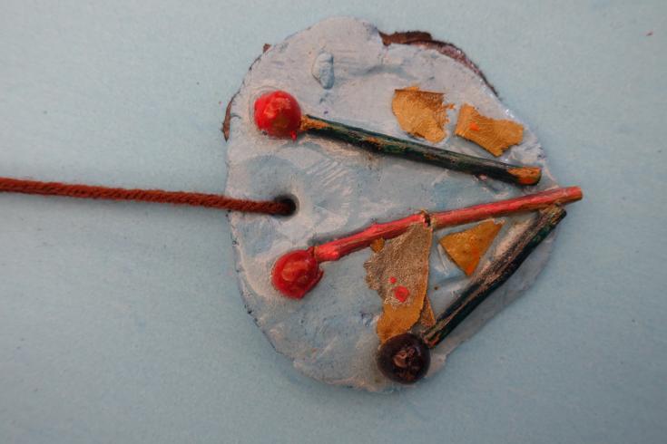 Clay mobile with holly, sticks, and leaves.