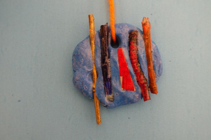 Clay mobile with painted sticks.