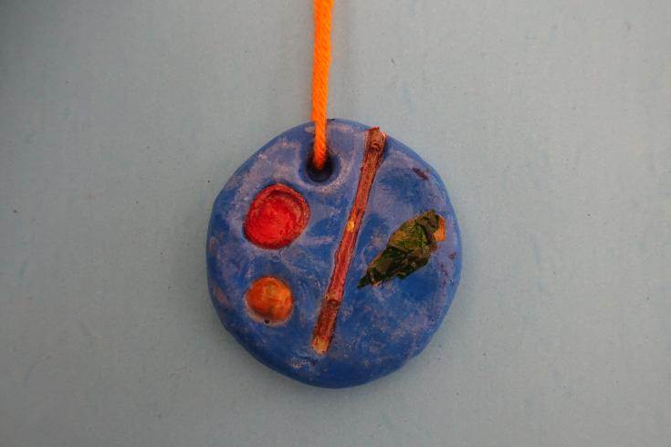 Clay mobile with a stick and painted acorns.
