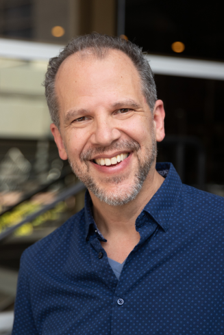 Headshot of Aaron Posner smiling wearing blue collared shirt