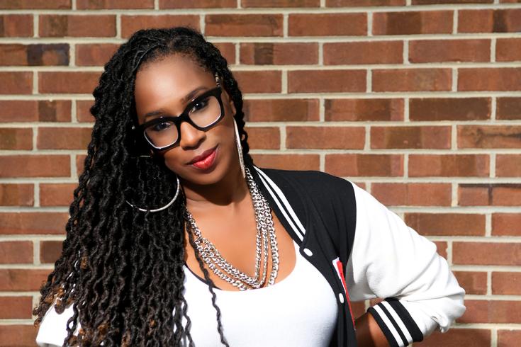 Headshot of DJ Miss H.E.R. in front of a brick wall