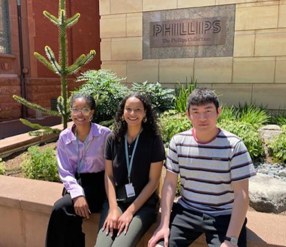 Three people sitting outside The Phillips Collection on a sunny day