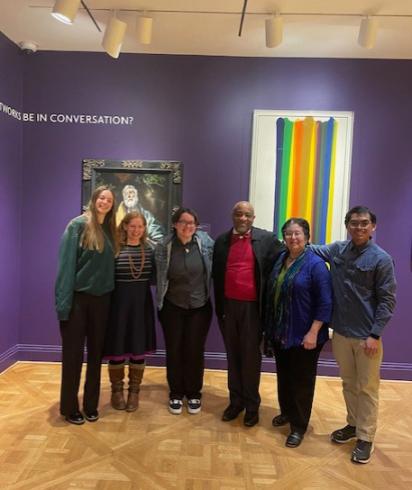 Group of six people standing in front of a purple wall with two artworks