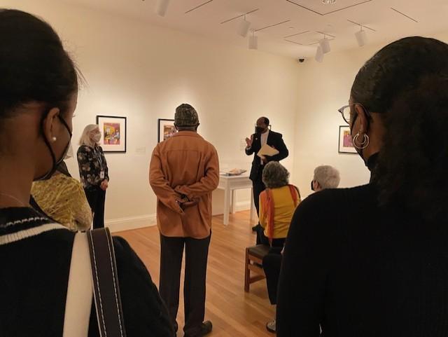 People in a gallery sitting and standing listening to a gallery talk
