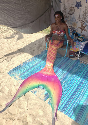 A person wearing a mermaid tail at the beach