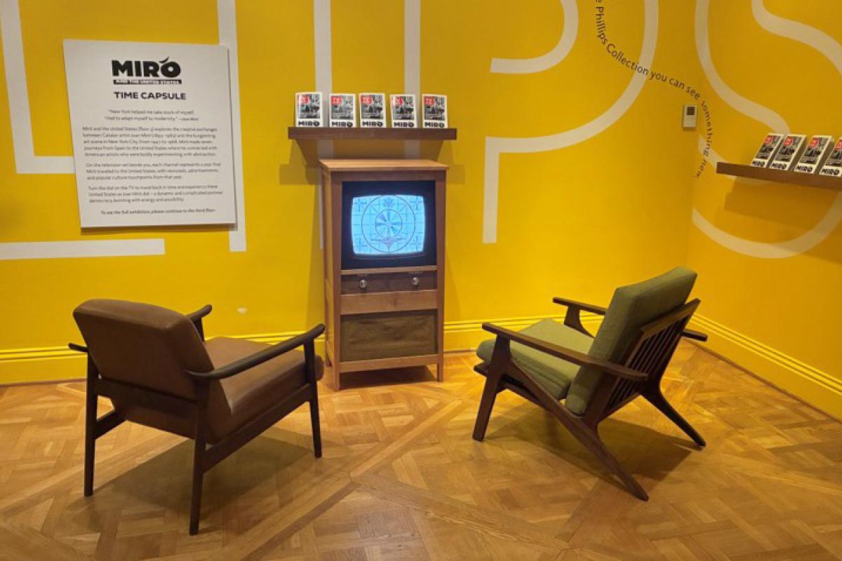 Two chairs in front of a retro tv against a yellow wall 